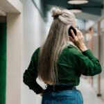 Rear view of a senior woman talking on a smartphone in a contemporary office setting.